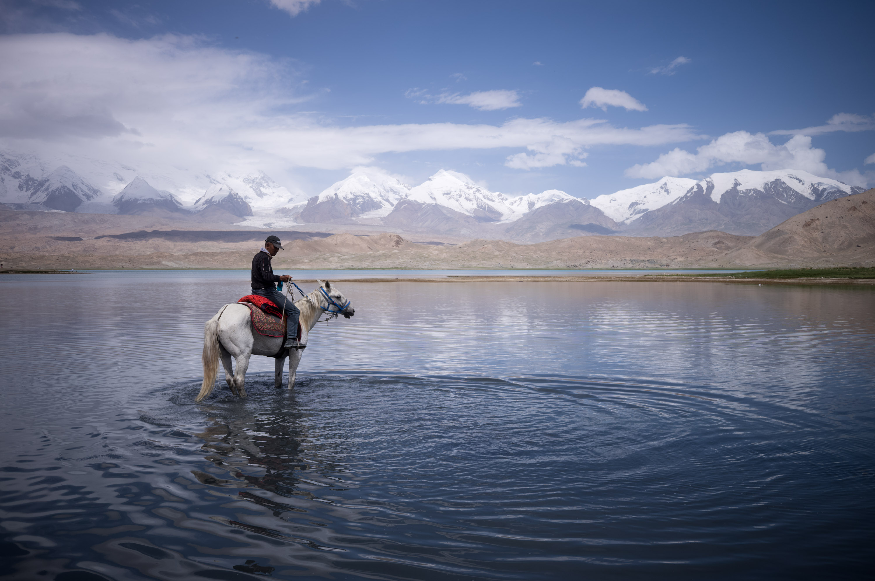 Local villagers offering horseback photo sessions for tourists at 20 yuan per ride. 当地村民在山下的湖边招揽游客生意，骑马拍照一次20元。